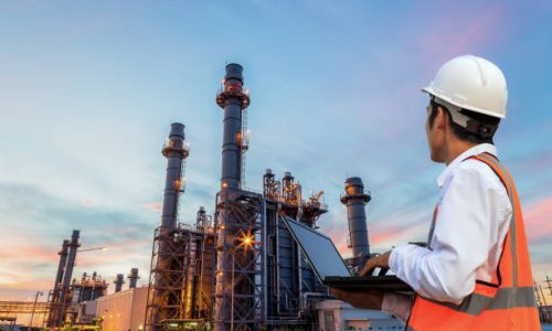 Engineering is use notebook check and standing in front of oil refinery building structure in heavy petrochemical industry